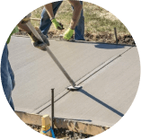 A man is laying concrete on a sidewalk with a shovel.