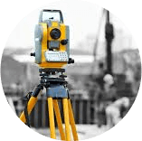 A yellow theodolite is sitting on top of a tripod on a construction site.