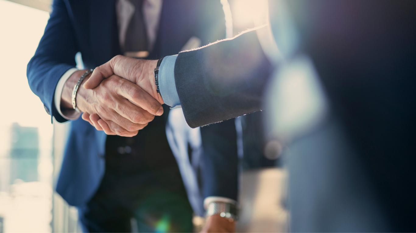 Two people in suits shaking hands; business agreement.