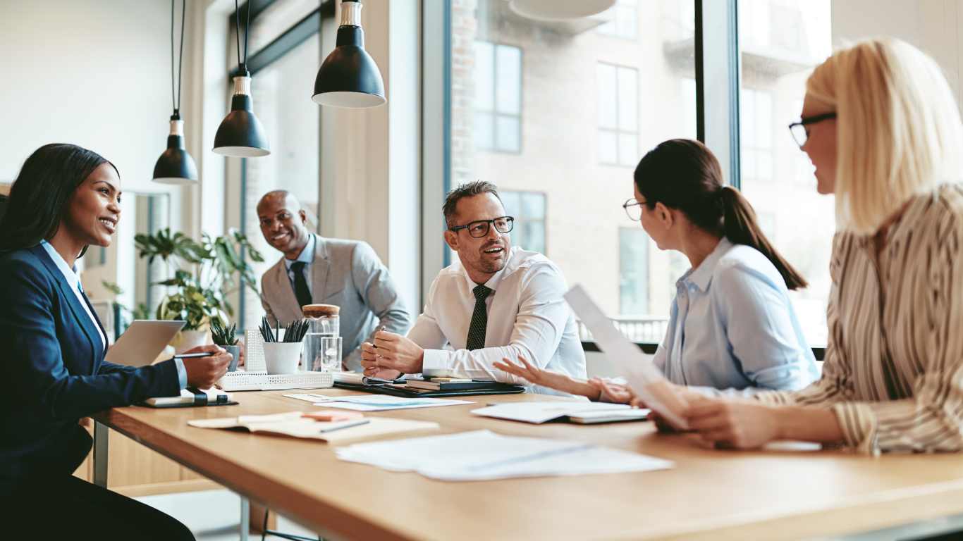 Business colleagues in a meeting at a table, discussing papers, in an office.