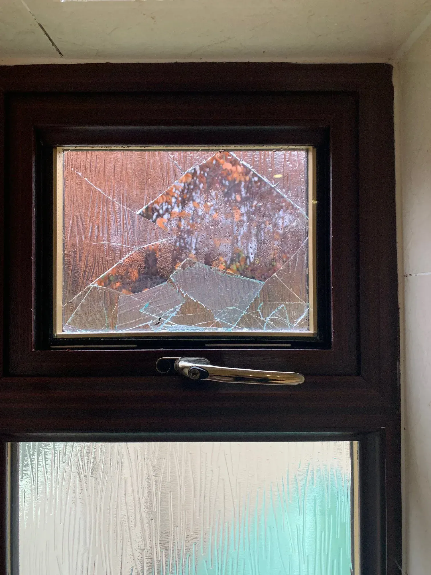 Broken brown window pane with shattered glass.