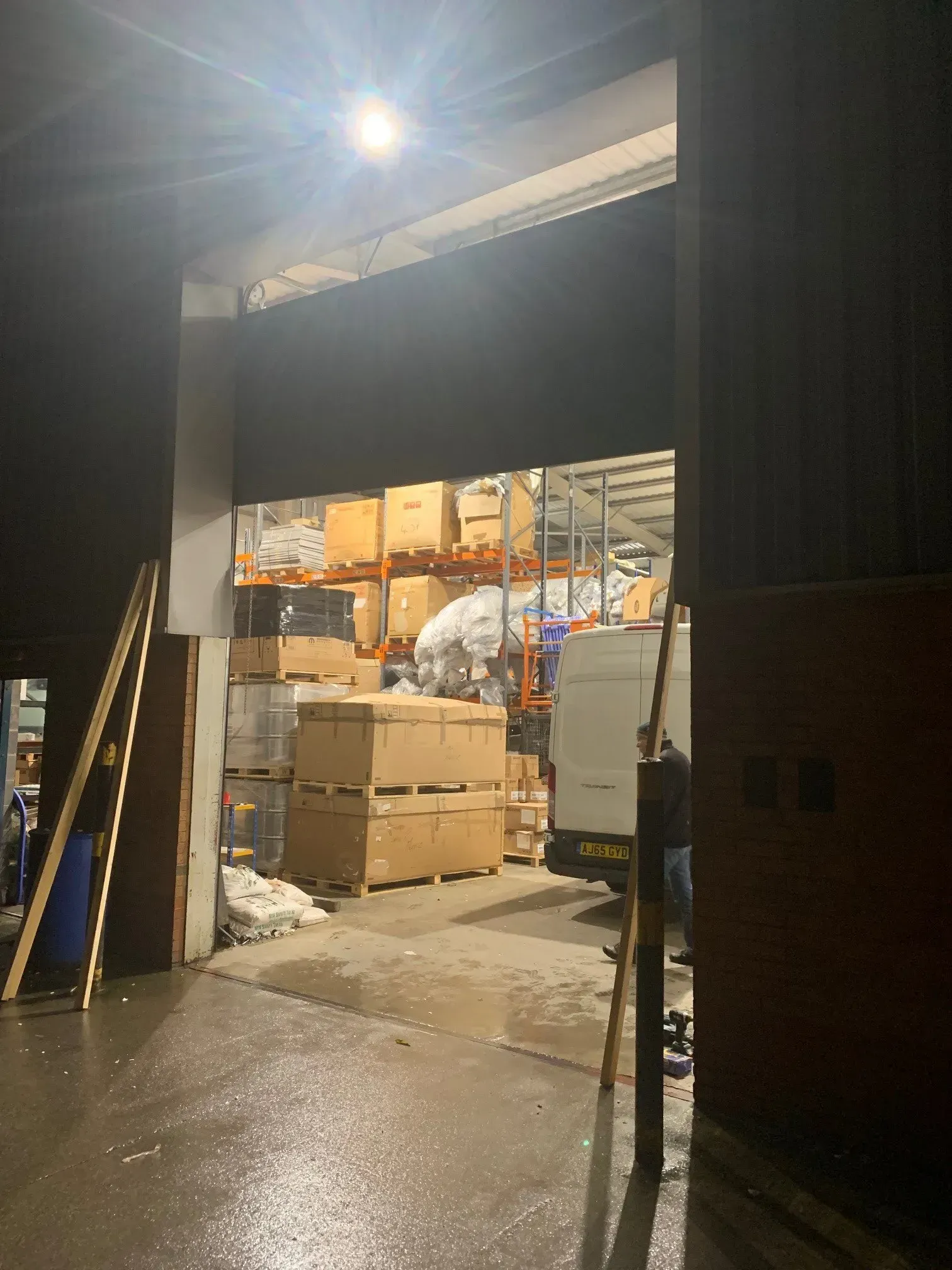 Warehouse loading dock, boxes stacked, lit doorway, interior shelving with products.