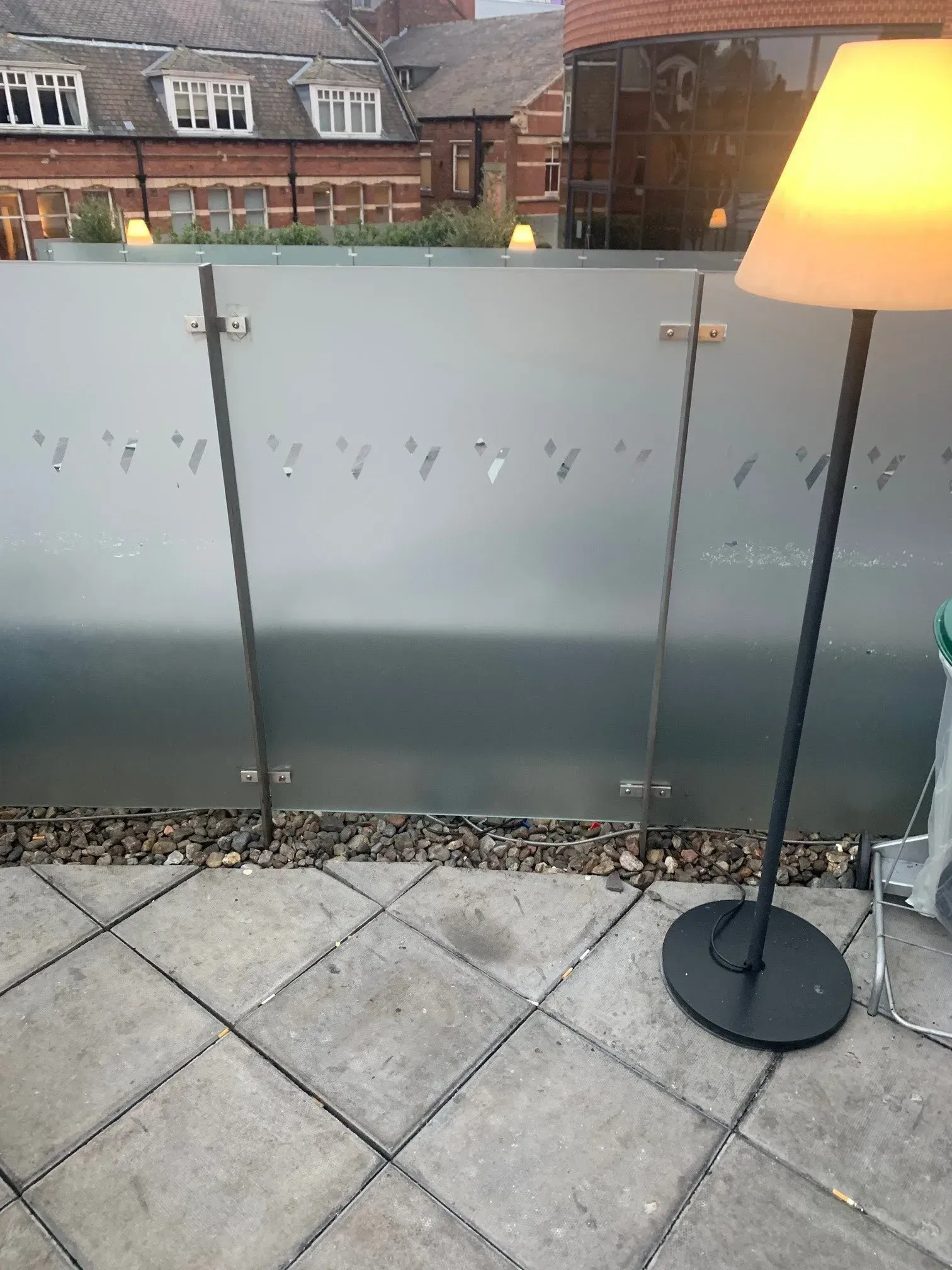 Frosted glass balcony with black lamp and gray stone tiles.