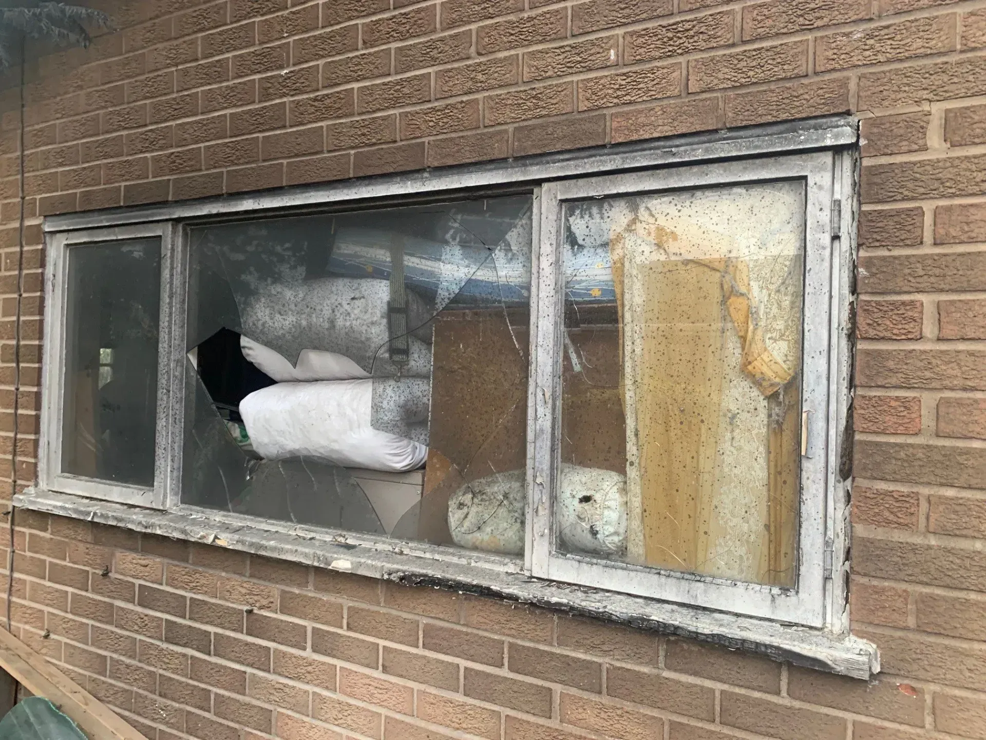 Broken window on a brick building; contents inside are visible through the glass.