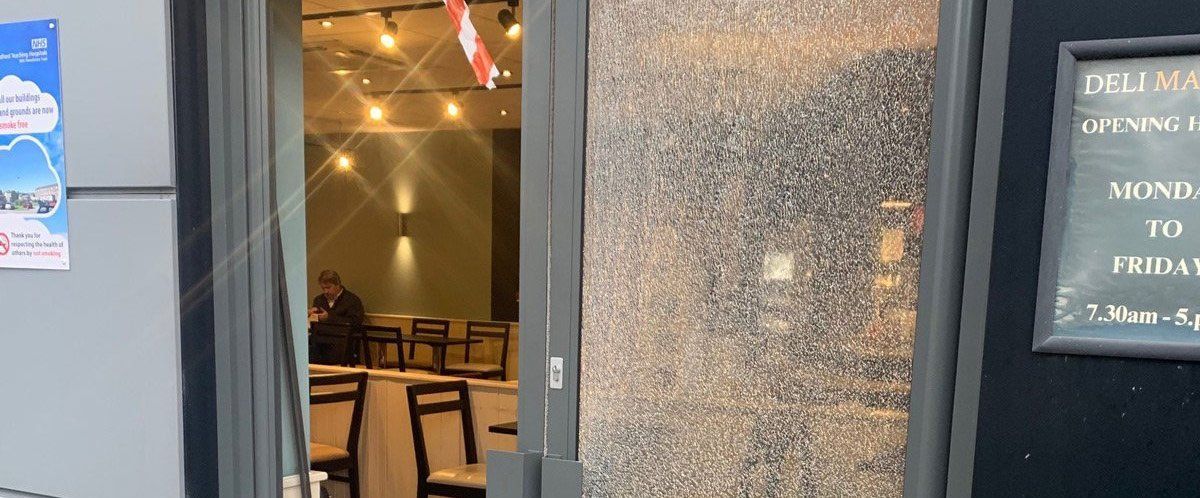 A restaurant entrance with a frosted glass door and a sign displaying the hours of operation. Inside, tables and chairs are visible.