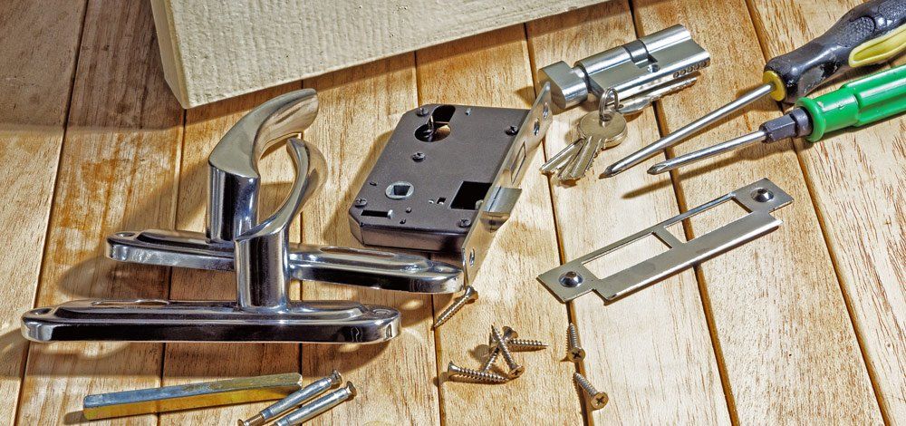 Door lock components and tools scattered on a wooden surface.