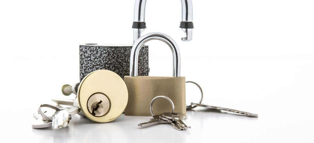 Close-up of three different locks and multiple keys arranged against a white backdrop.