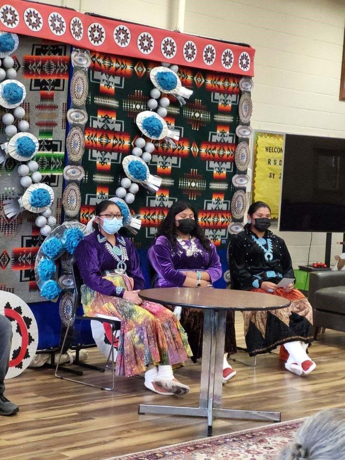 A group of people wearing masks are sitting at a table.