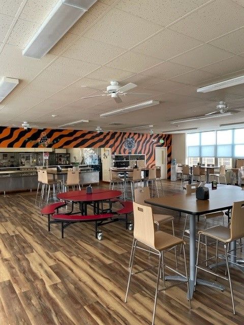 A large dining room with tables and chairs and a tiger print on the wall.