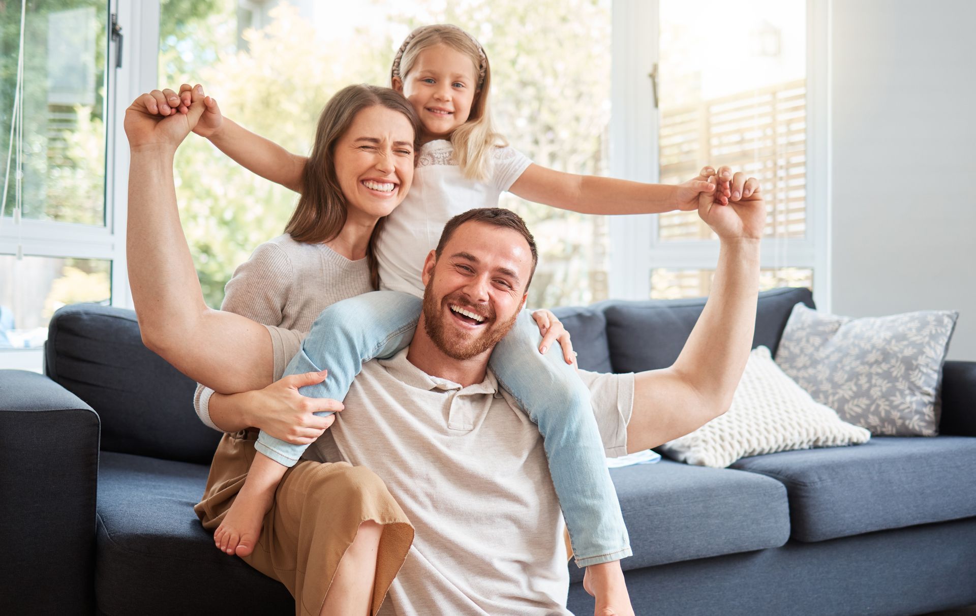 A smiling family of three in a living room.