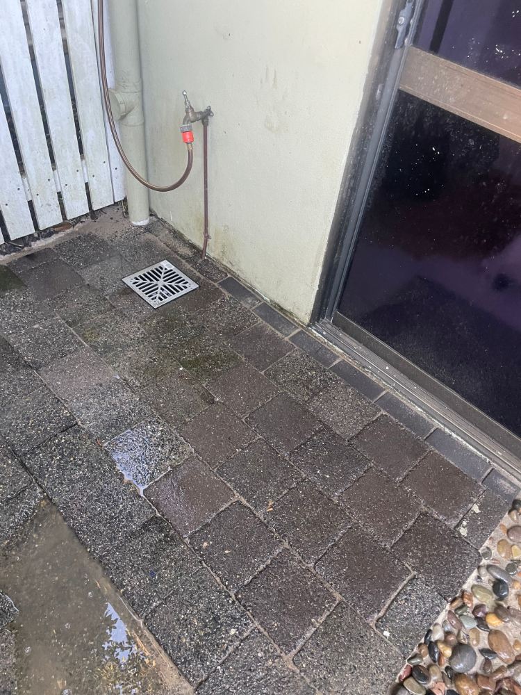 Brick pavers with a drain and water spigot next to a door — Smooth Flow Plumbing Cairns in Cairns City, QLD
