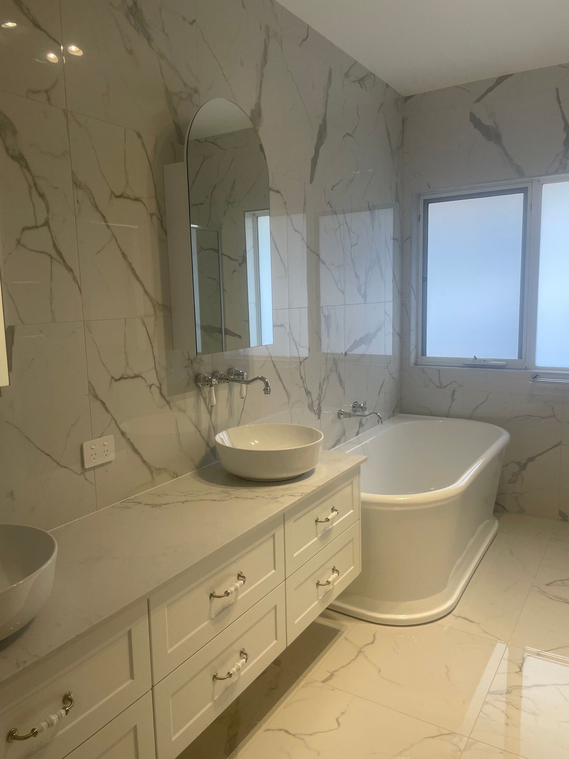 Elegant bathroom with marble-look tiles, a freestanding tub, and a vanity with two vessel sinks — Smooth Flow Plumbing Cairns in Cairns City, QLD 