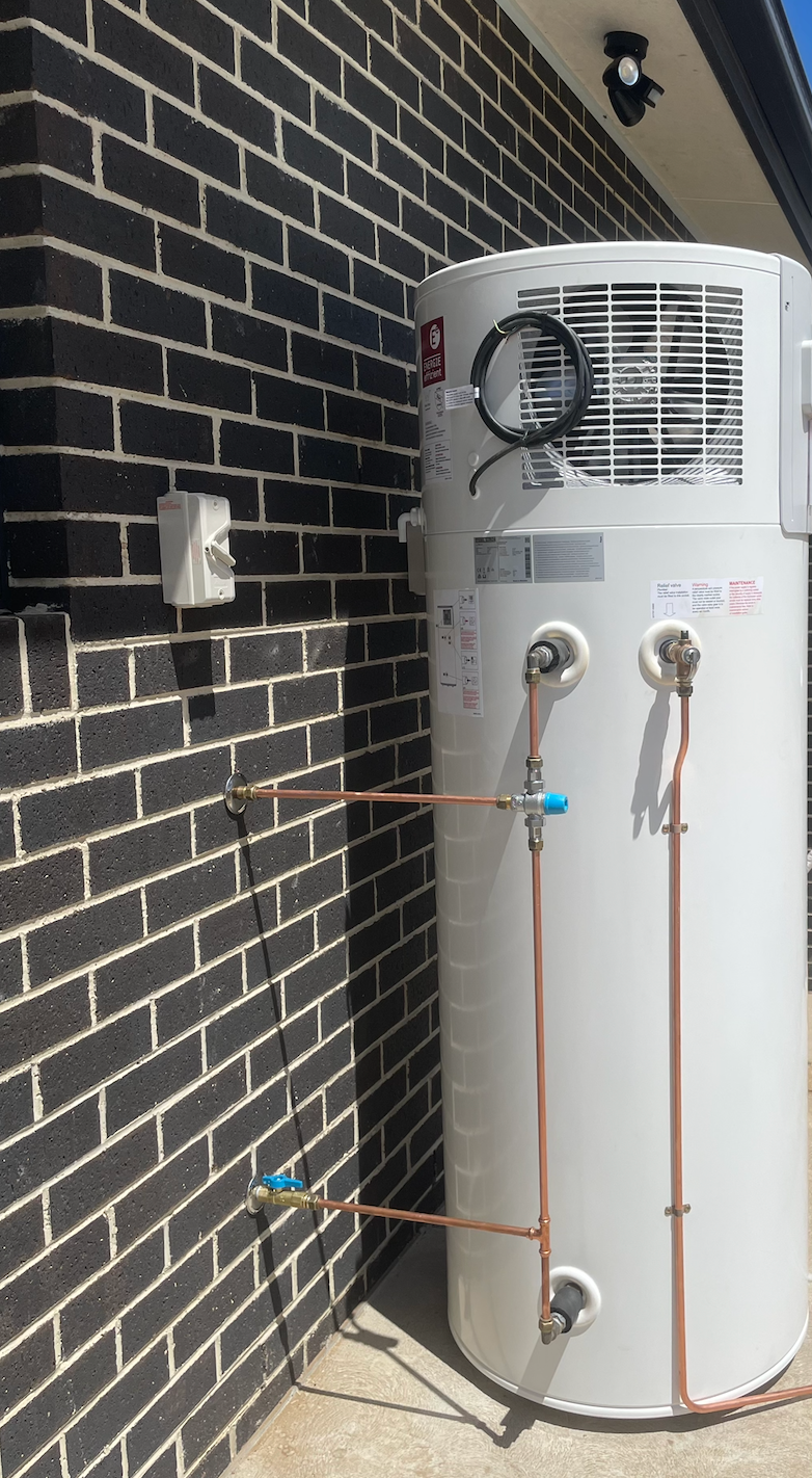 A Man is Fixing a Boiler With a Wrench and a Screwdriver — Smooth Flow Plumbing Cairns in Cairns City, QLD 