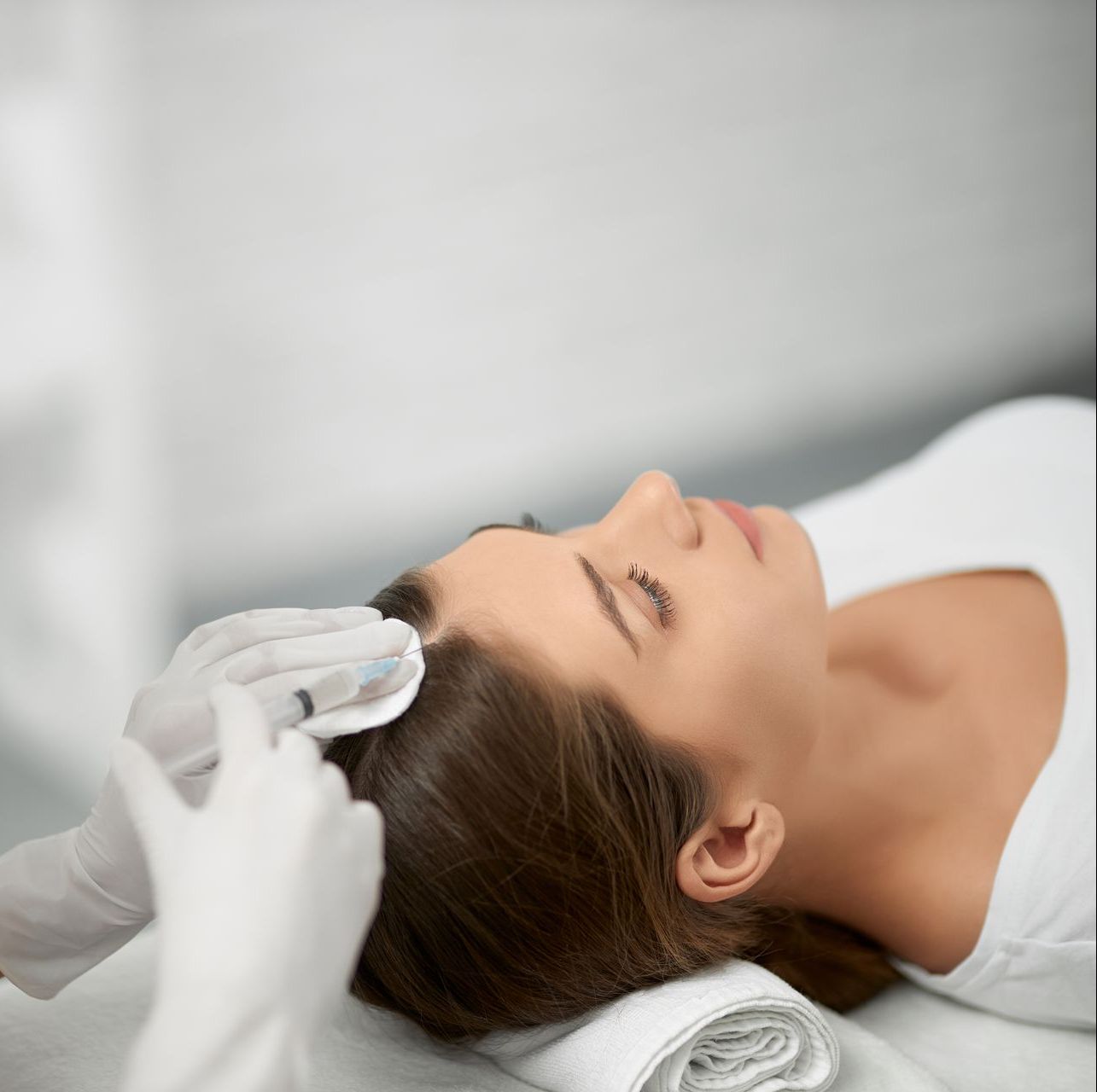 a woman is laying on a bed getting a PRP treatment