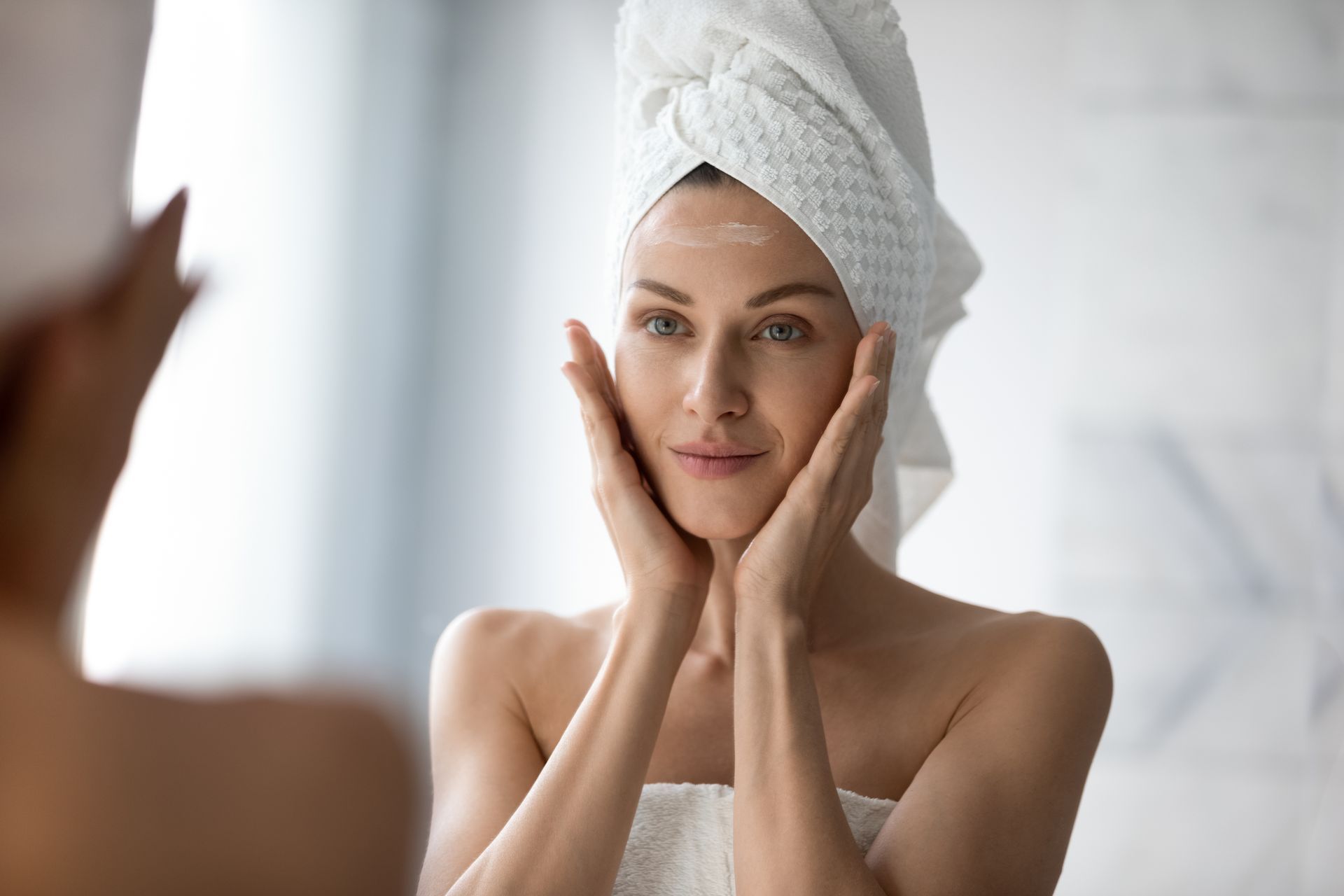 a woman with a towel wrapped around her head is looking at her face in the mirror 