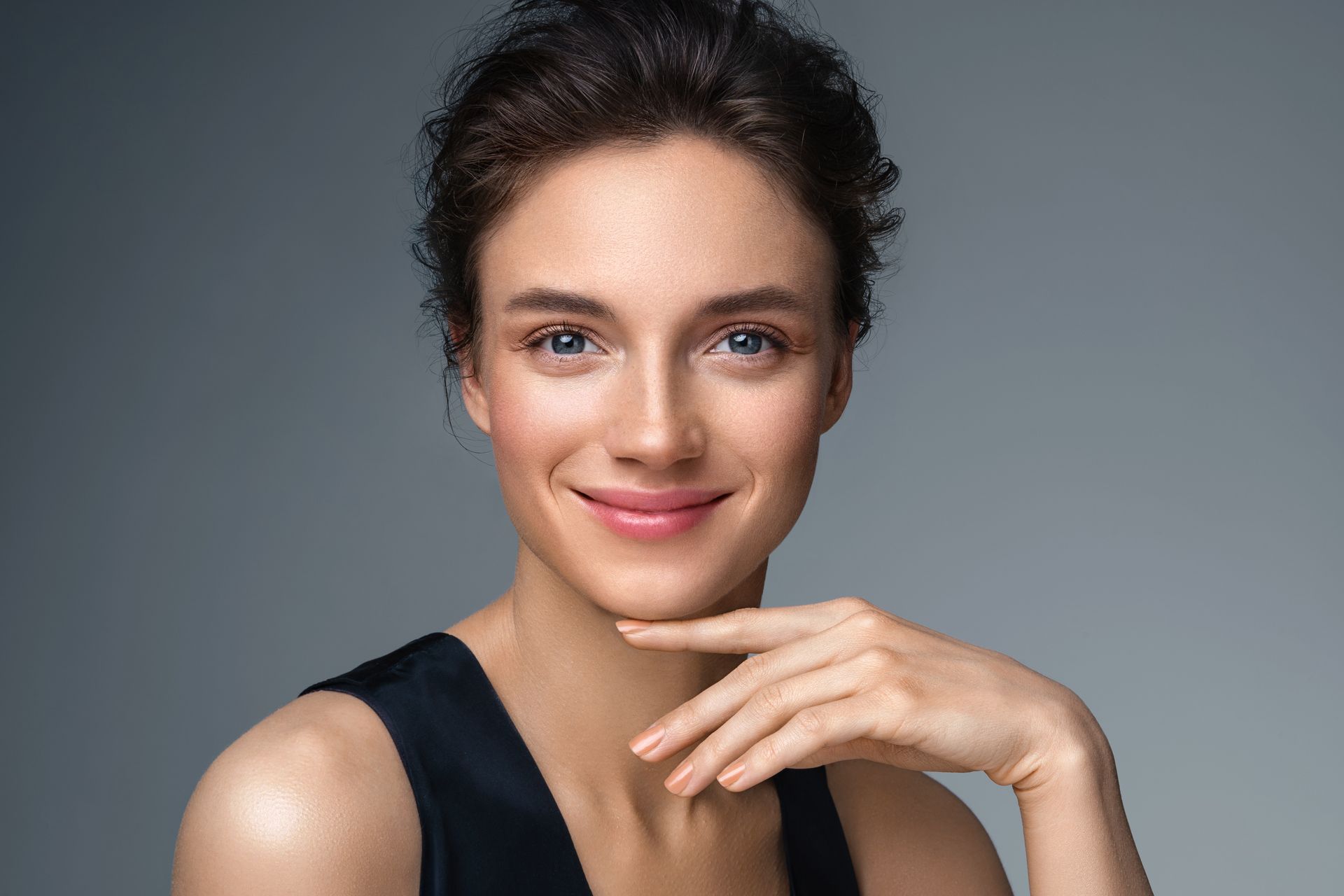 a woman is smiling and touching her face with her hand .
