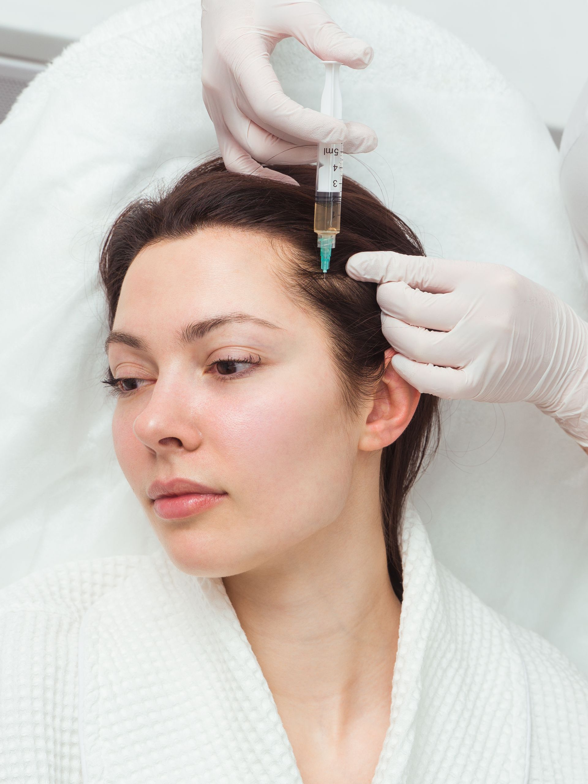 a woman is getting a PRP injection in her head