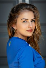 A close up of a woman wearing a blue shirt and earrings.