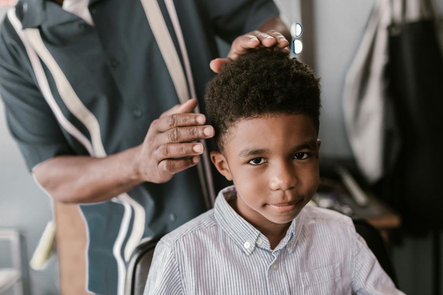 A young boy is getting his hair cut by a barber.
