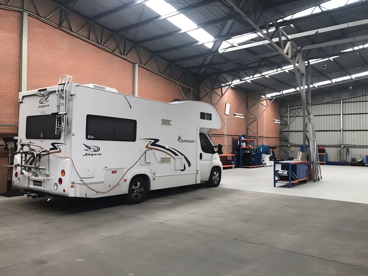 A Man is Working on a White Van on a Lift in a Garage — Truckserv In Yallah, NSW