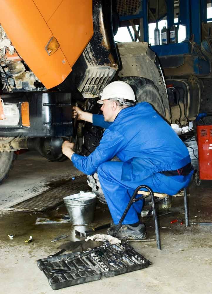 A Man Is Working On A Truck In A Garage — Truckserv In Yallah, NSW