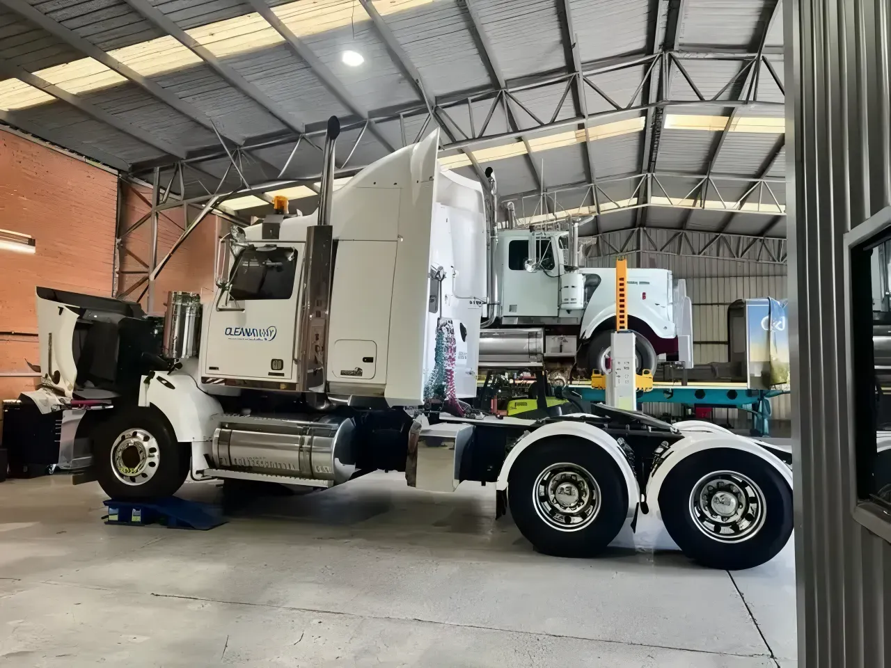 A Man in Blue Overalls is Working on a Truck — Truckserv In Yallah, NSW