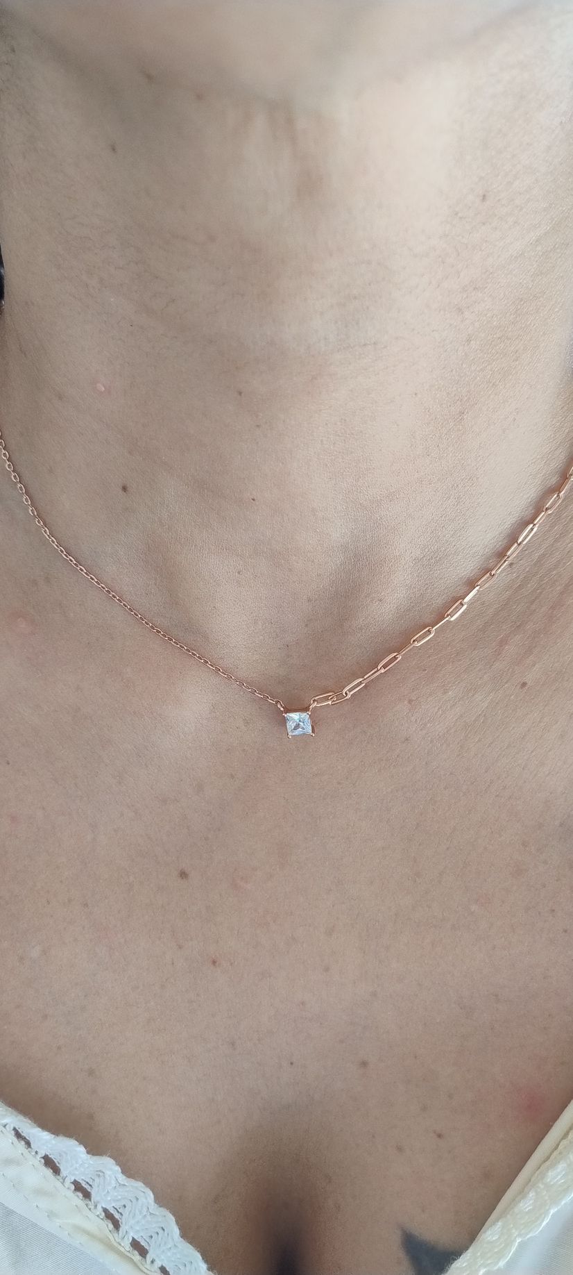 Primer plano de un delicado collar de oro con un pequeño colgante azul en el cuello de una persona.