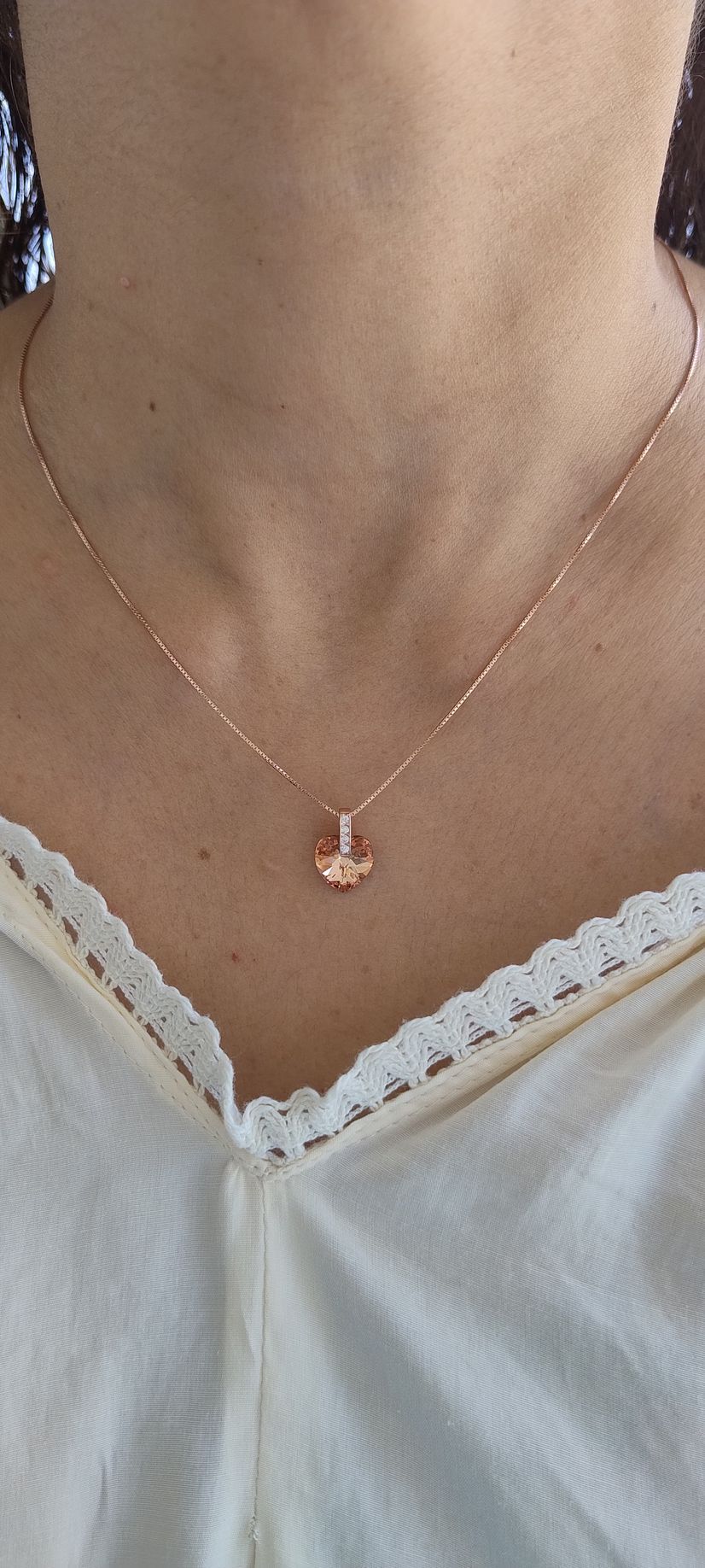 Primer plano de una persona que lleva un delicado collar de oro y una blusa blanca con ribete de encaje.