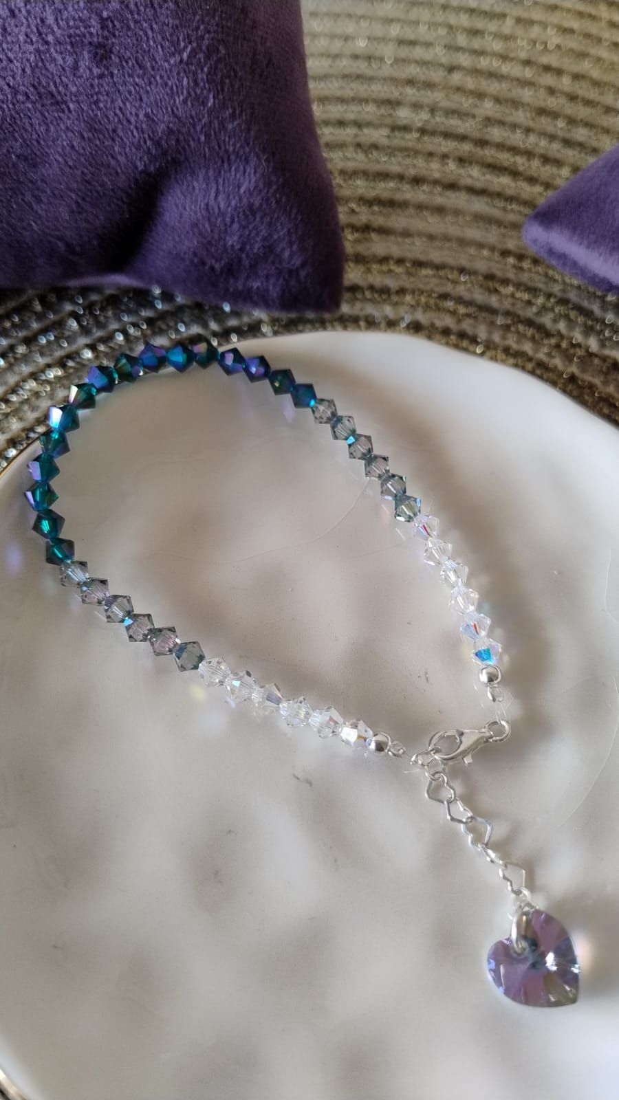 Una pulsera con un colgante en forma de corazón reposa sobre un plato blanco.