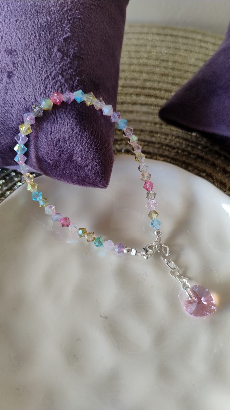 Una pulsera reposa sobre un plato blanco al lado de una servilleta morada.