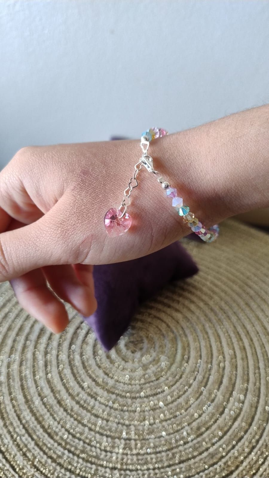 Una pulsera reposa sobre un plato blanco al lado de una servilleta morada.