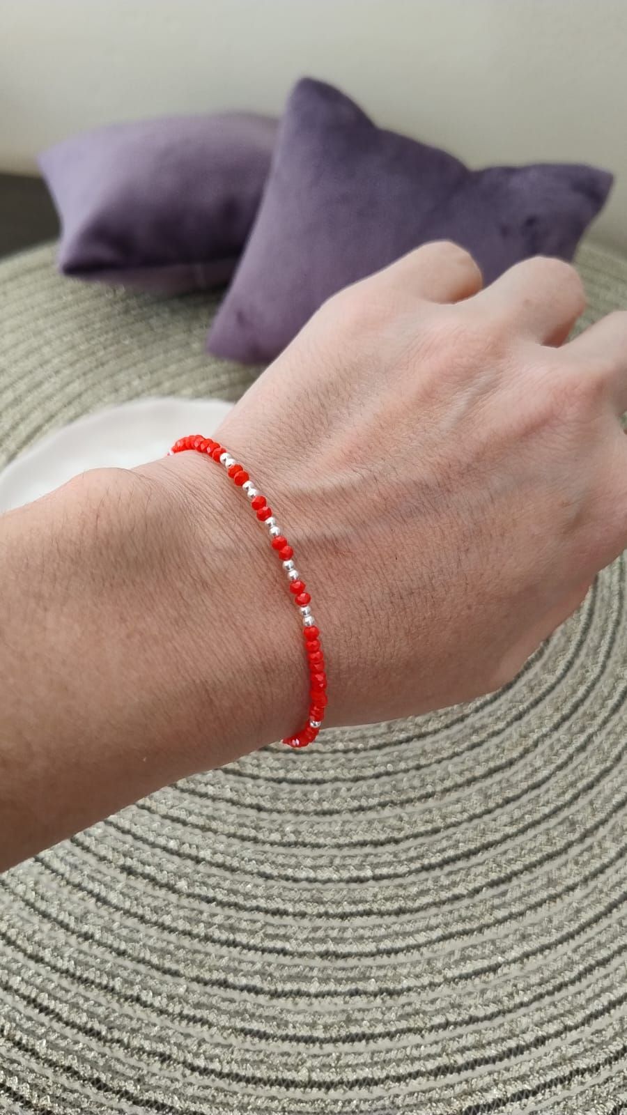 Una persona lleva una pulsera de cuentas rojas en su muñeca.