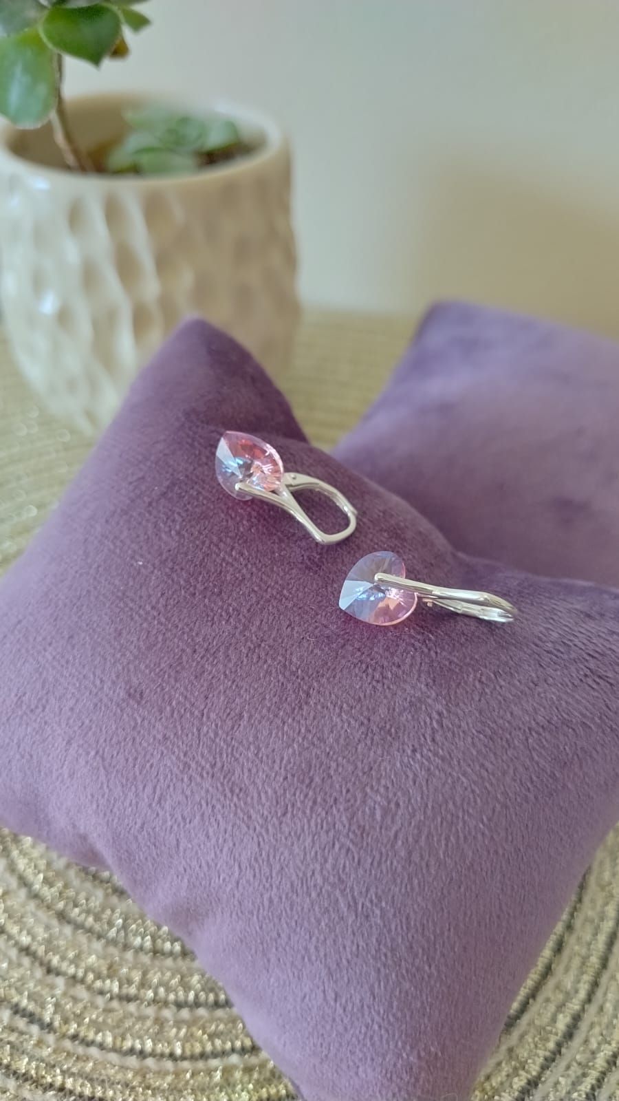 Un par de pendientes están colocados encima de una almohada morada.