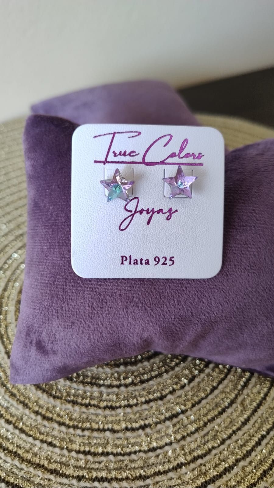 Un par de pendientes encima de una almohada morada.