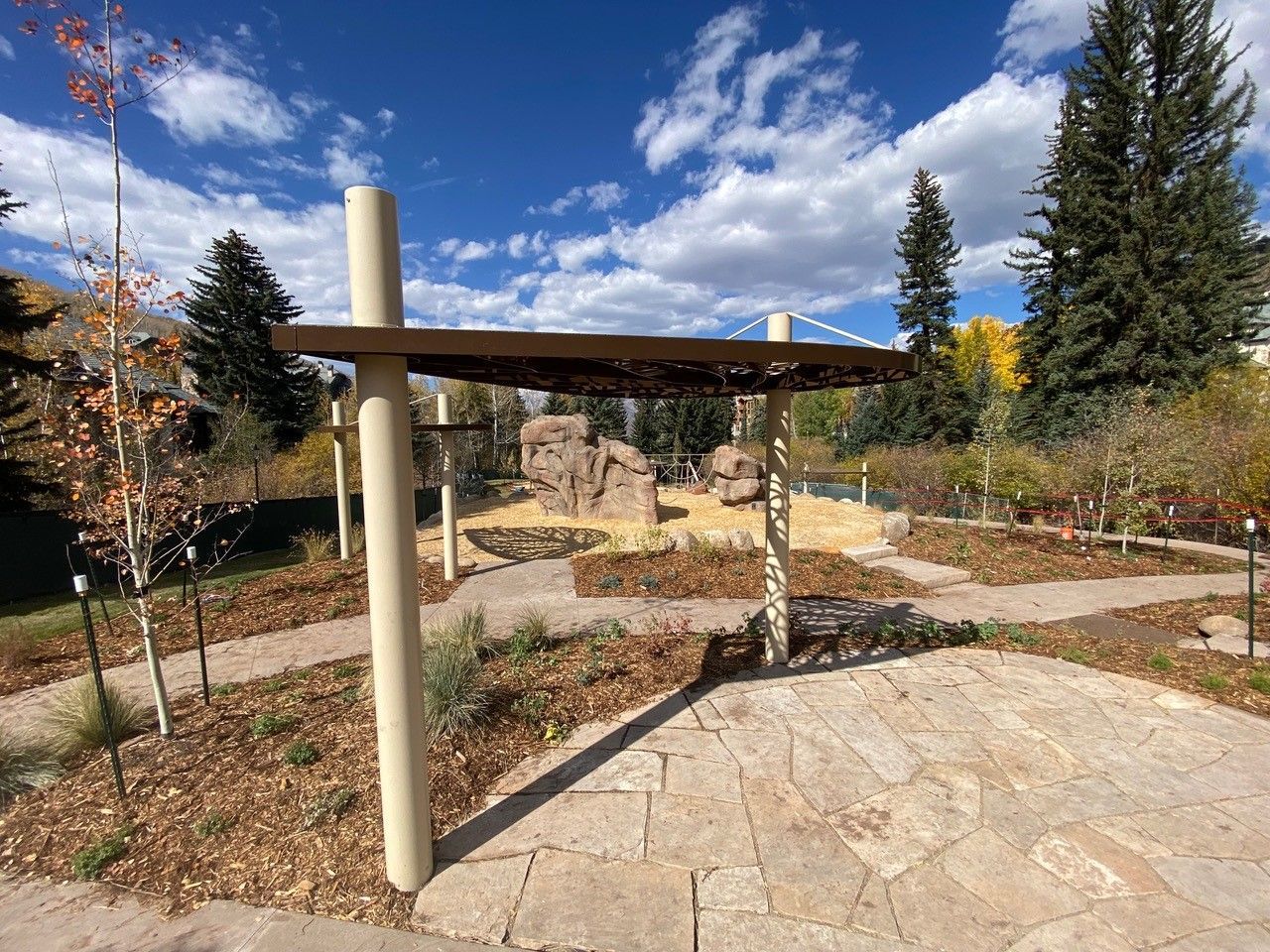 A wooden pergola is sitting in the middle of a park.