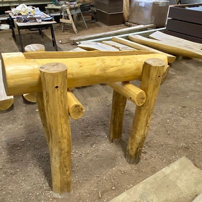 A wooden bench made out of logs is sitting on the ground.