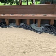 A wooden bench is sitting on top of a sandy beach.