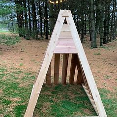 A wooden a frame is sitting in the middle of a forest.