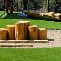 A row of wooden stump benches sitting on top of a lush green field.