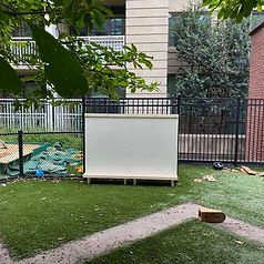 A white board is sitting on top of a lush green field next to a fence.