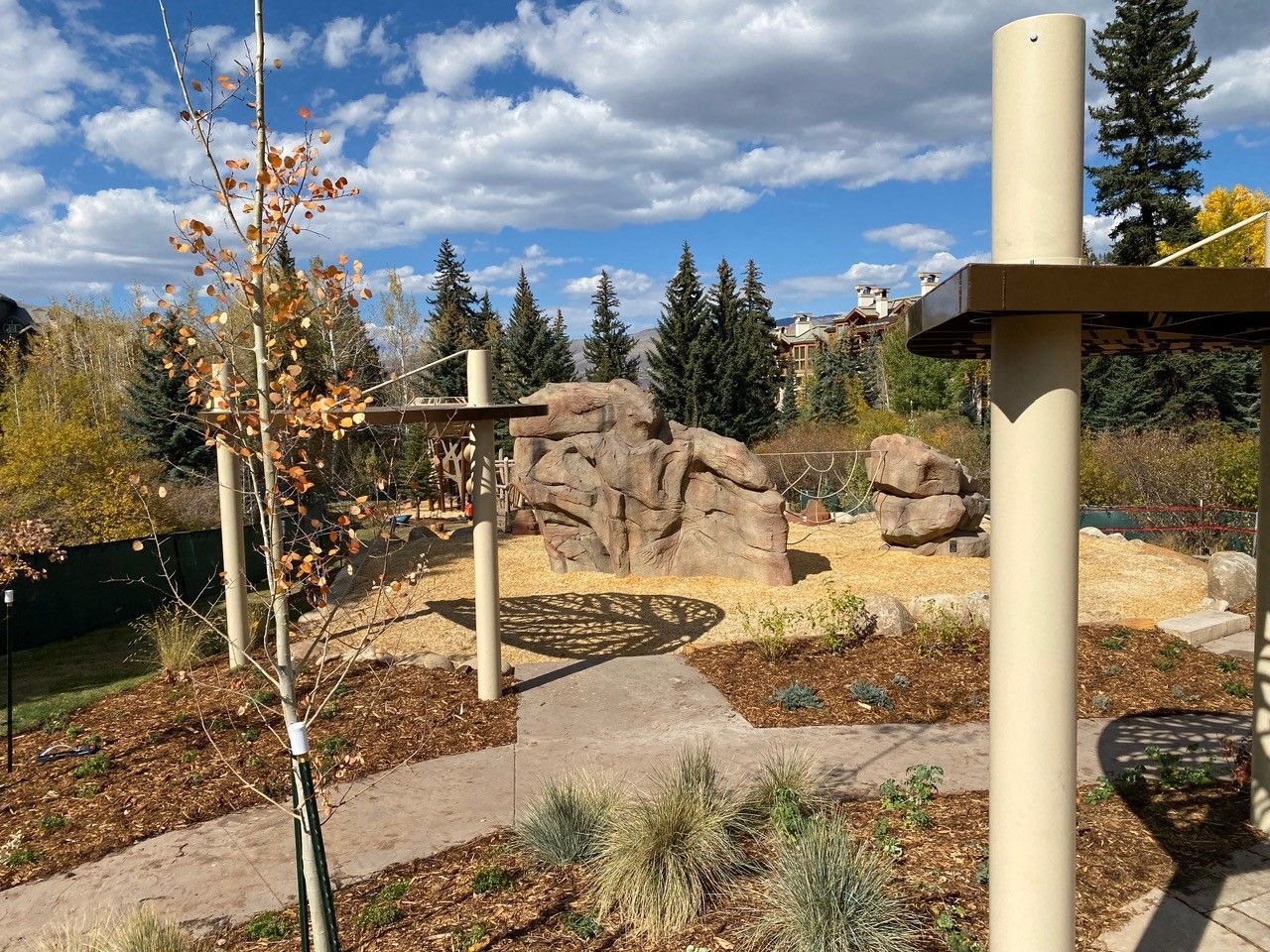 A playground with a ropes course and a swing in the middle of a park.