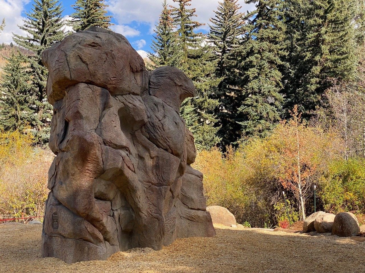 A large rock formation in the middle of a field with trees in the background.
