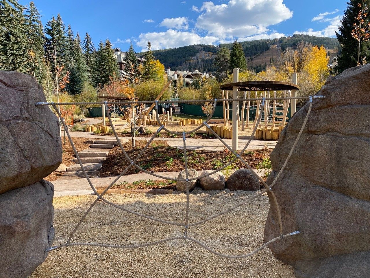 A view of a playground from between two large rocks.