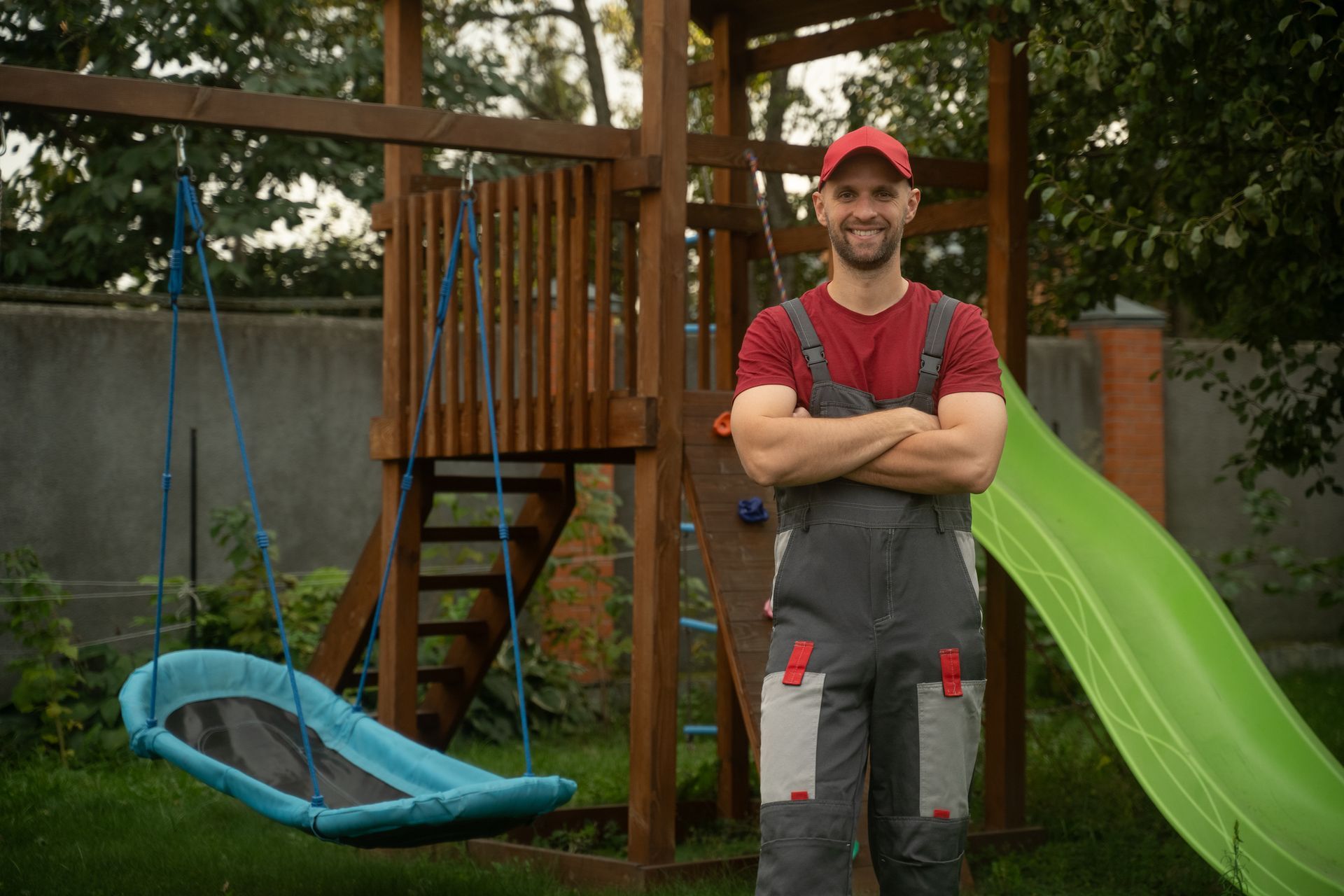 A construction worker stands with arms crossed in front of a playground.