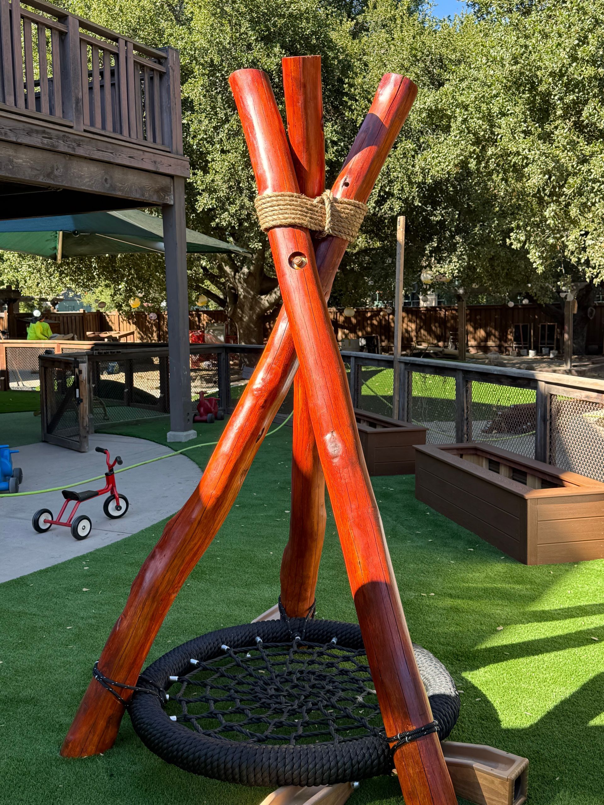 A wooden swing set is sitting on top of a lush green hill in a park.