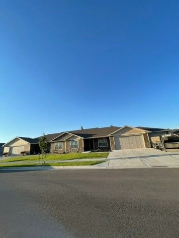 Suburban homes with brown exteriors, tan garage doors, and a clear blue sky.