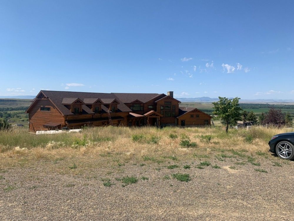 Woman in straw hat smiles, holding wine glass near a lake.