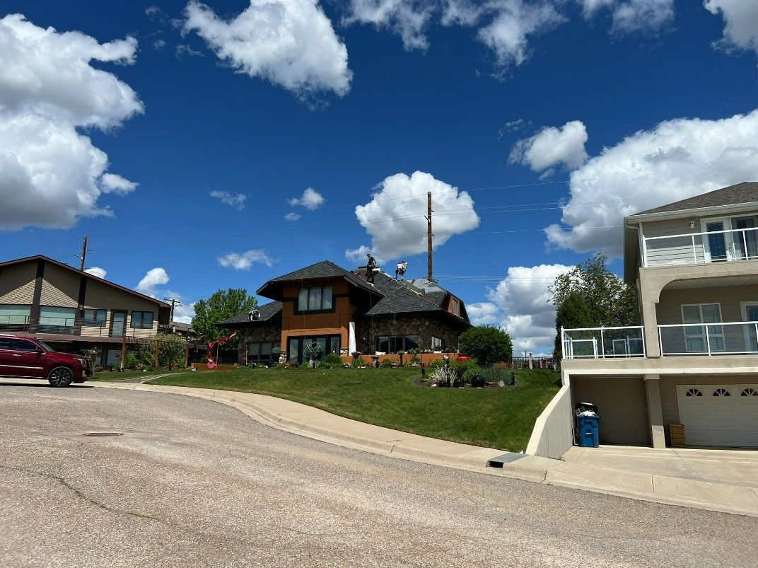Woman in straw hat smiles, holding wine glass near a lake.