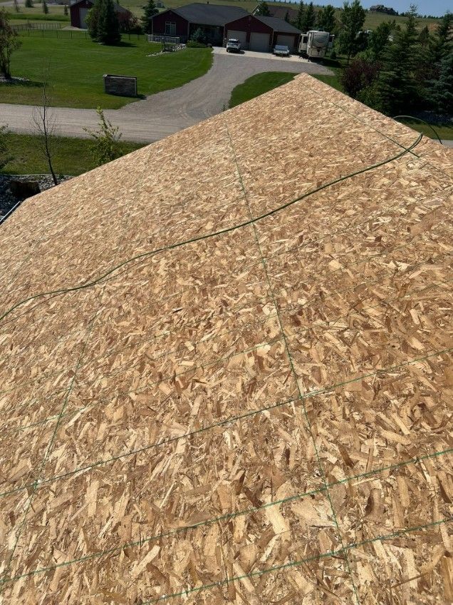Woman in straw hat smiles, holding wine glass near a lake.