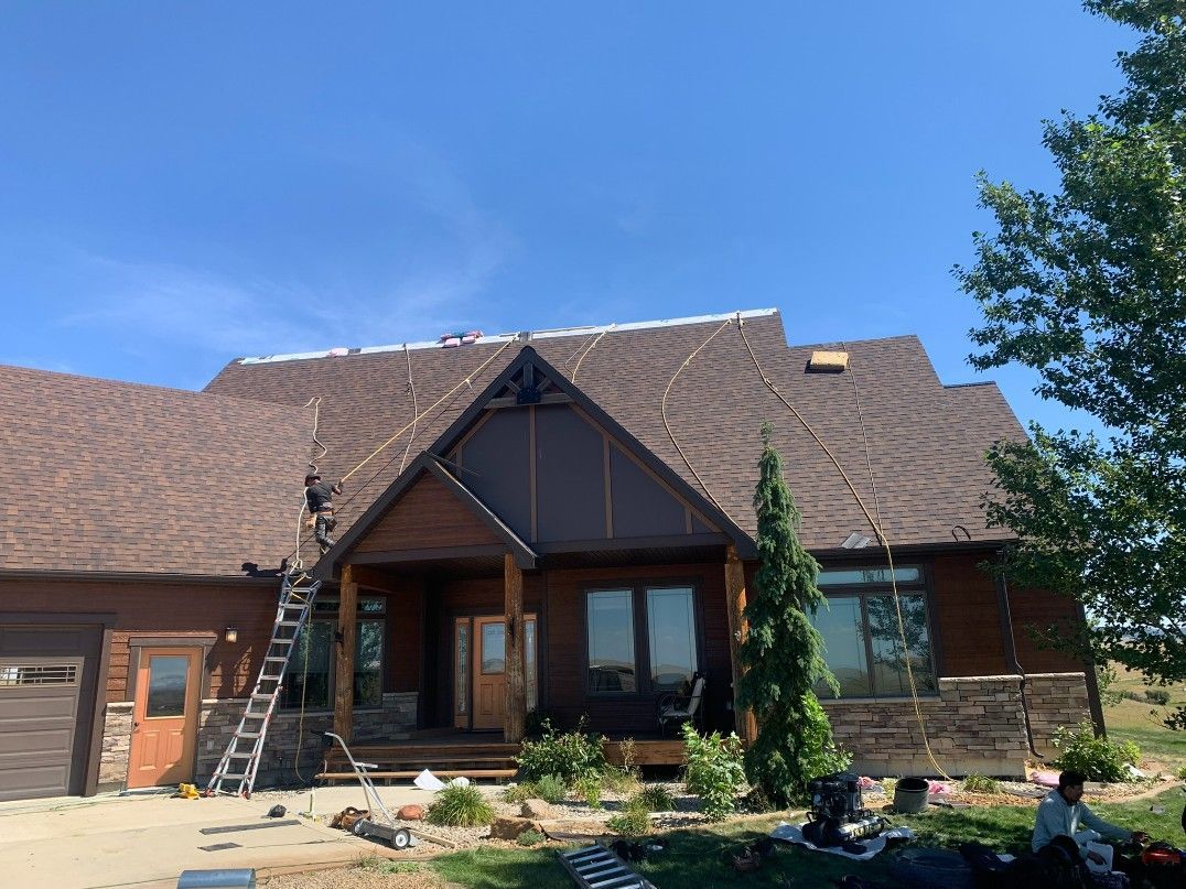 Woman in straw hat smiles, holding wine glass near a lake.